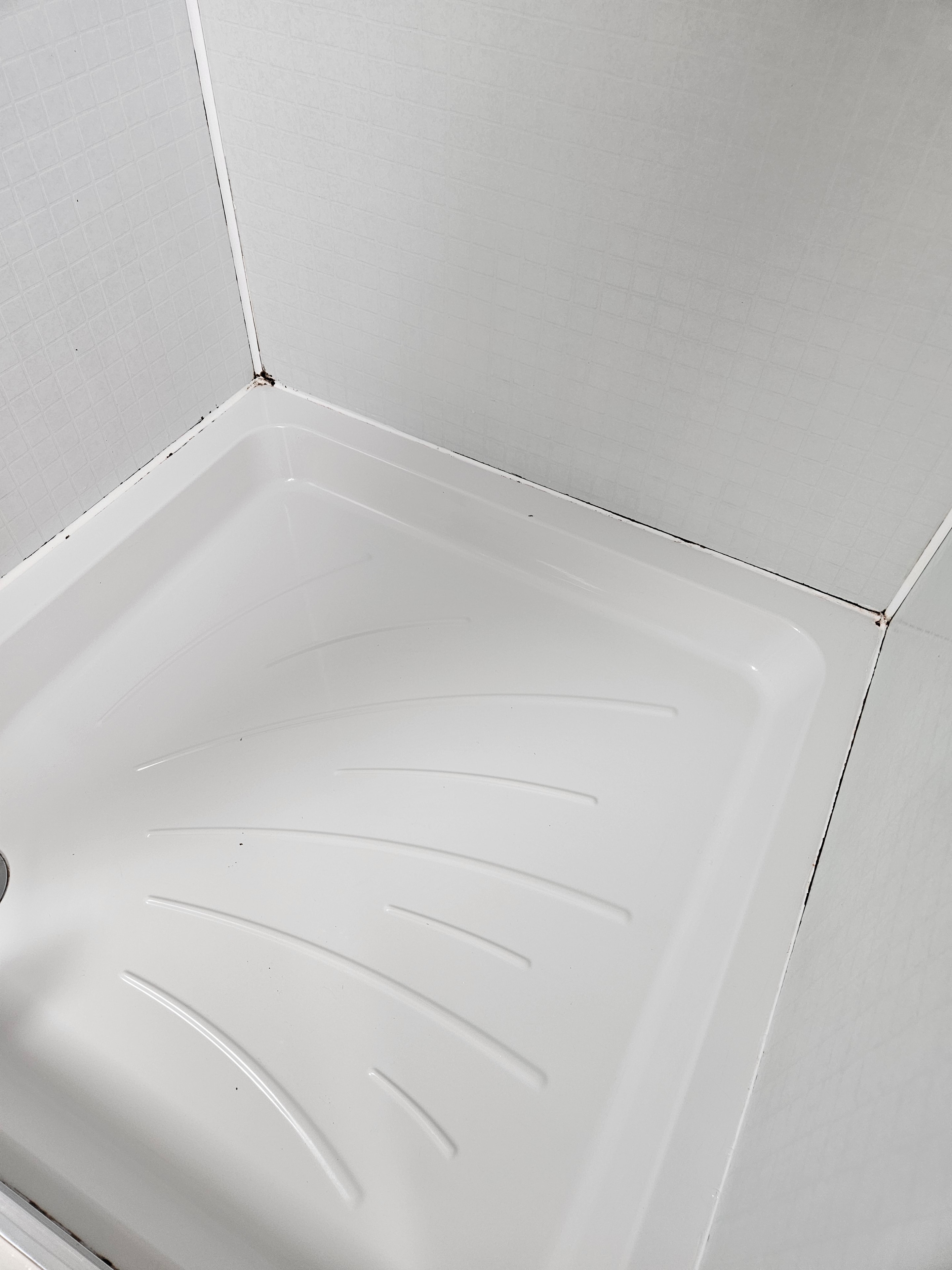 Shower tray before old mouldy sealant was removed in Anglesey